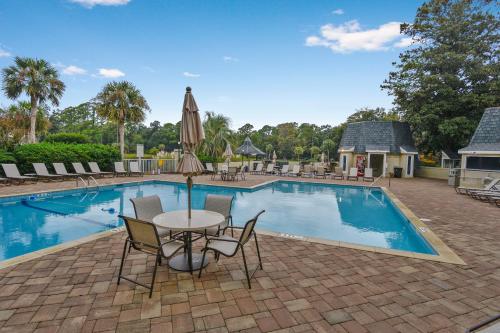 a pool with chairs and a table with an umbrella at Evian 156 in Hilton Head Island