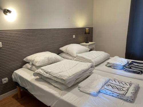 zwei Betten in einem Zimmer mit weißen Laken und Kissen in der Unterkunft LES ILES VUE SUR MER in Agon Coutainville
