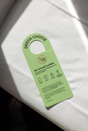 a green tag sitting on top of a bed at Fred Guest House Hauptbahnhof - Mobile Check-in in Zürich
