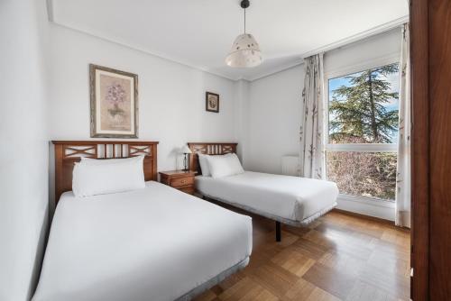 two beds in a room with a window at Apartamentos El Cid in Burgos
