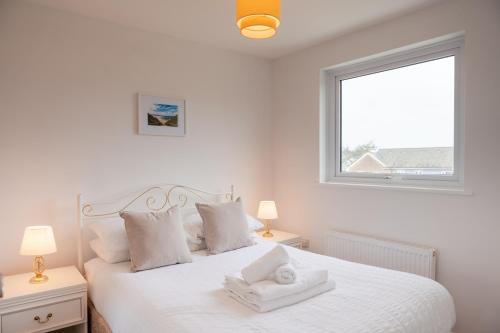 ein Schlafzimmer mit einem weißen Bett mit zwei Lampen und einem Fenster in der Unterkunft Olivera House in Redruth