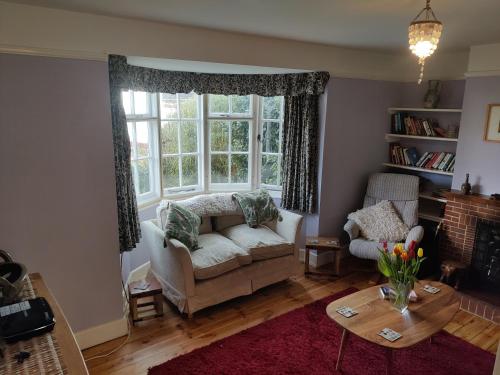 a living room with a couch and a large window at April cottage in Winchelsea