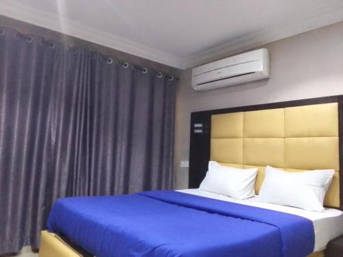 een slaapkamer met een bed met blauwe lakens en een blauwe deken bij Hotel bougainvillea Victoria island in Lagos