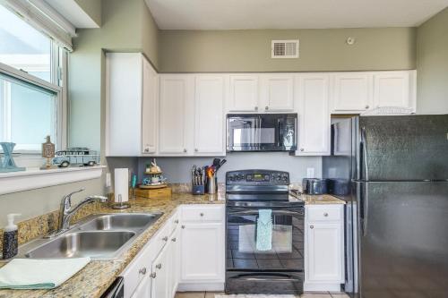 a kitchen with white cabinets and a stainless steel refrigerator at Gulfport Oceanfront Vacation Rental Walk to Beach in Gulfport