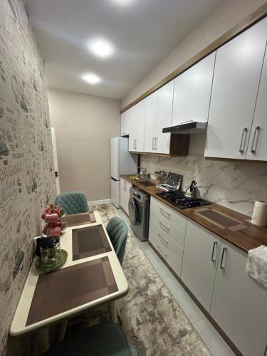Apartment for tourists في سمرقند: مطبخ مع دواليب بيضاء وطاولة وكراسي