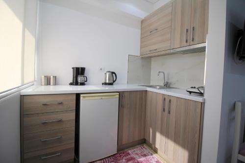una piccola cucina con mobili in legno e una lavastoviglie bianca di Elena Hotel a Sarandë