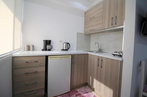 a small kitchen with wooden cabinets and a white dishwasher at Elena Hotel in Sarandë