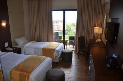 a hotel room with two beds and a balcony at Hotel Monticello Tagaytay in Tagaytay