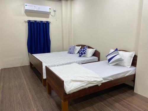 Habitación con 2 camas y cortina azul en Ujjayini Home Stay en Ujjain