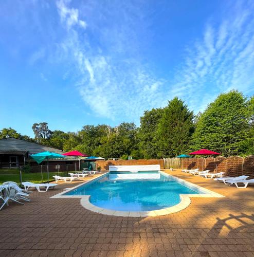 une grande piscine avec chaises et parasols dans l'établissement Chalets Moulière Evasion, à Montamisé