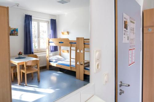 a small room with a bunk bed and a table at Jugendherberge Lübeck Vor dem Burgtor in Lübeck