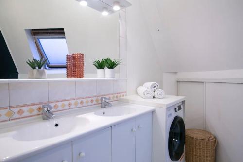 une salle de bains blanche avec deux lavabos et un lave-linge. dans l'établissement Skyline Parisian Flat - Exclusif Saint-Honoré, à Paris