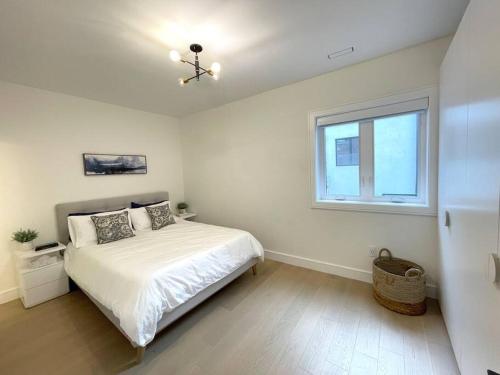 a white bedroom with a bed and a window at Modern Apartment Close To The Beach with Parking in Toronto