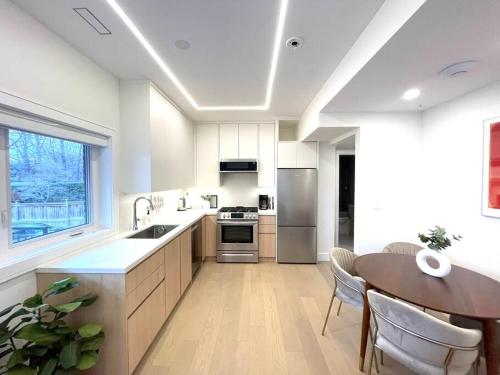 a kitchen with white cabinets and a table and a counter at Modern Apartment Close To The Beach with Parking in Toronto
