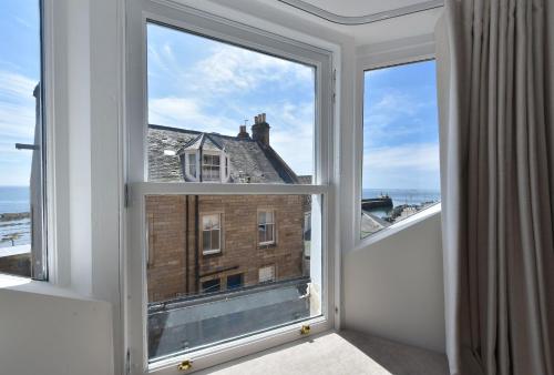 an open window with a view of a building at Penthouse on the Harbour - Pittenweem in Pittenweem