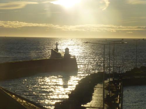 a ship in the ocean with the sun in the sky at Penthouse on the Harbour - Pittenweem in Pittenweem