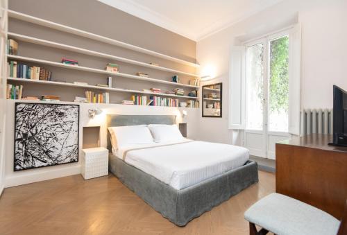 Schlafzimmer mit einem Bett, einem TV und Bücherregalen in der Unterkunft Raffaello Apartment by Firenze Prestige in Florenz