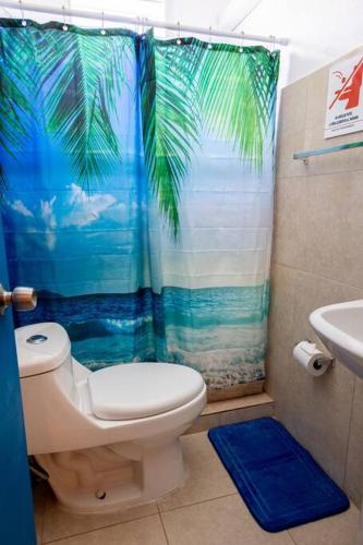 a bathroom with a toilet and a tropical shower curtain at Studio 3 Anacaona with Garden access in Vieques