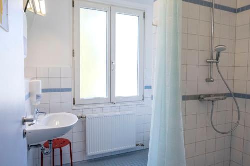 a bathroom with a sink and a shower with a window at Jugendherberge Lübeck Vor dem Burgtor in Lübeck