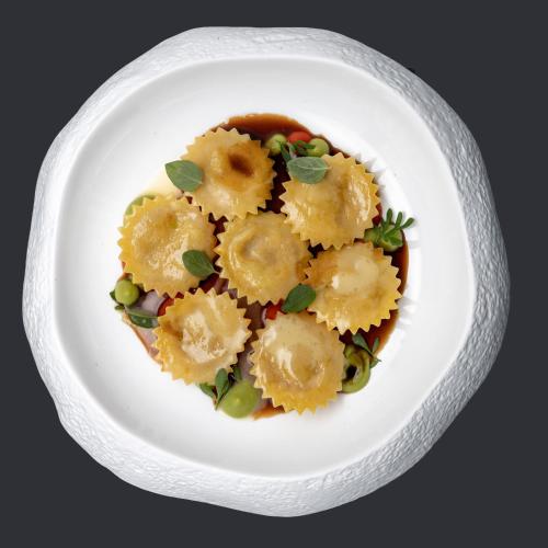 a white plate with a dish of ravioli and vegetables at LUGANODANTE Boutique & Lifestyle Hotel in Lugano