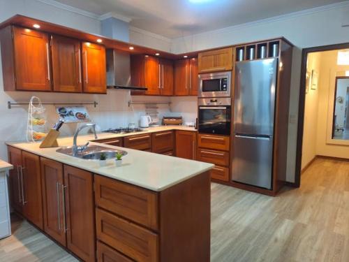 a kitchen with wooden cabinets and a stainless steel refrigerator at Garden House in São Vicente Ferreira