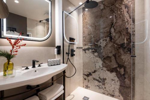 La salle de bains est pourvue d'un lavabo et d'une douche. dans l'établissement Hôtel L'Ormaie & Spa, à Paris