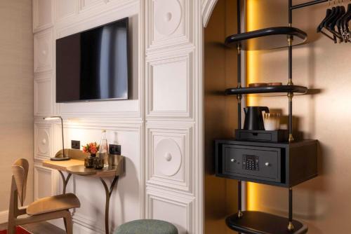 Habitación con pared, microondas y mesa. en Hôtel L'Ormaie & Spa en París