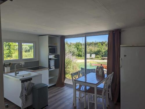 a kitchen with a table and a dining room with a view at Chalet climatisé en campagne avec baignade privée in Lagnes
