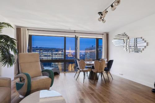 - un salon avec une table, des chaises et une grande fenêtre dans l'établissement Paris luxury Apartment 75m2 with Eiffel Tower View, metro 1 min, parking, à Paris