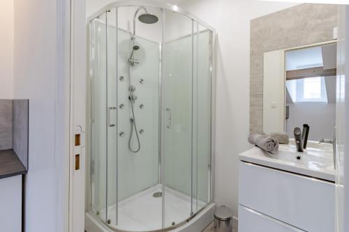een glazen douche in een badkamer met een wastafel bij D'am Chic Nomade Appartement bleu in Périgueux