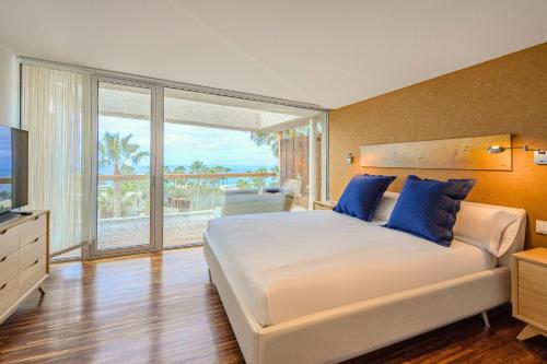 a bedroom with a large bed and a large window at Stunning Sunsets Abama in Playa de San Juan
