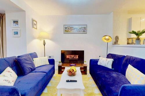 sala de estar con sofá azul y TV en Dale House, Spacious Home in Central Dartford with Parking, en Kent