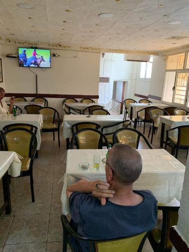 Ein Mann, der an einem Tisch in einem Restaurant sitzt. in der Unterkunft Hotel les Remparts in Sicca Veneria