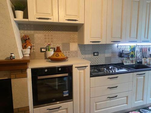 Una cocina con gabinetes blancos y un horno de estufa. en Grazioso appartamento, en Pieve Santo Stefano