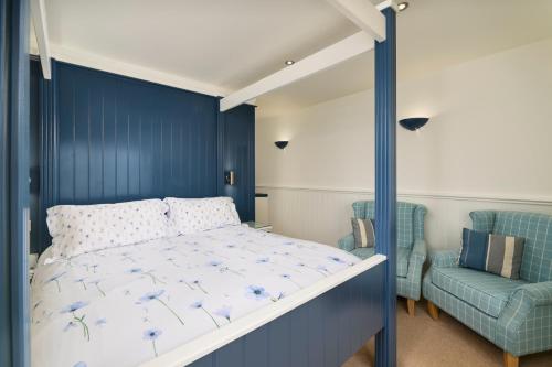 a bedroom with a bed and a blue wall at The Cricket Inn in Beesands
