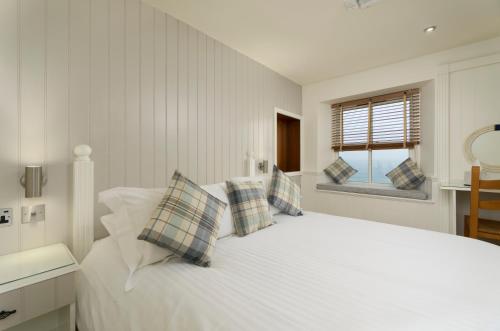 a white bedroom with a large white bed with pillows at The Cricket Inn in Beesands
