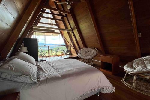 1 dormitorio con cama y ventana grande en Vista panorámica de Laguna Azul en Sauce-San Martín en Sauce