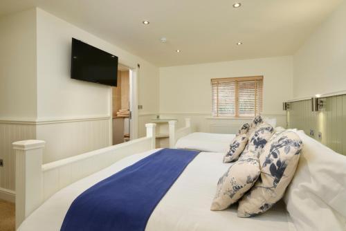 a bedroom with a large bed with blue and white pillows at The Cricket Inn in Beesands