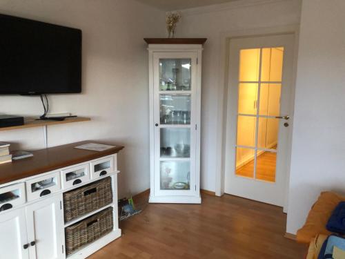 a living room with a television and a door to a kitchen at Rosenalm App 23 in Scheidegg