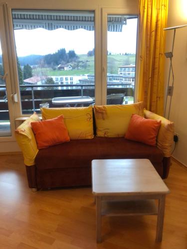 a living room with a couch with pillows and a table at Rosenalm App 23 in Scheidegg
