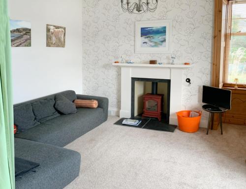 a living room with a couch and a fireplace at Sandbankhouse Campbeltown in Campbeltown
