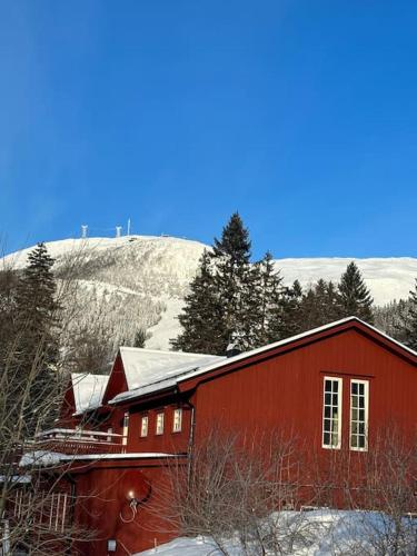 a red barn with a snow covered mountain in the background at Bagargården7. bed & breakfast (Åre Bageri) in Åre