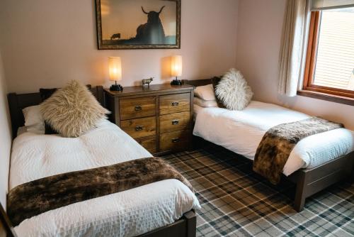 a bedroom with two beds and a dresser at Eriskay B&B and Aviemore Glamping in Aviemore
