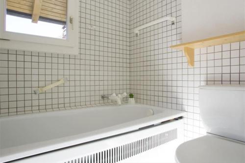 La salle de bains blanche est pourvue d'une baignoire et de toilettes. dans l'établissement Chalet La Madelon idéal pour les grandes familles, à Hérémence