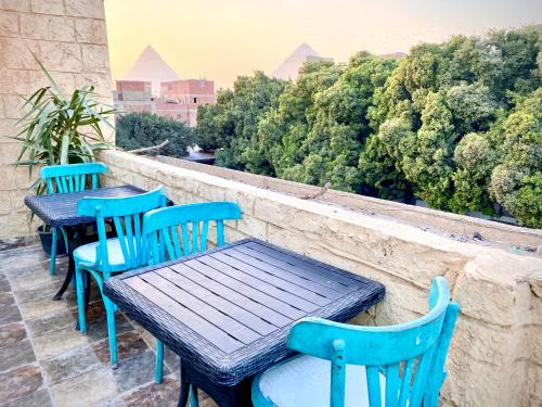 trois tables et chaises bleues sur un balcon arboré dans l'établissement 4 Pyramids inn, au Caire