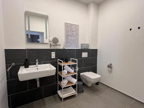een badkamer met een wastafel, een toilet en een spiegel bij AMAYA LIVING 80qm Japandi Krefeld Zentrum in Krefeld