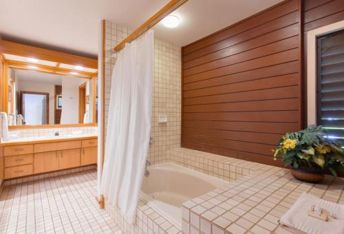 uma casa de banho com uma banheira, um lavatório e um espelho. em 412 Ridge em Kahana