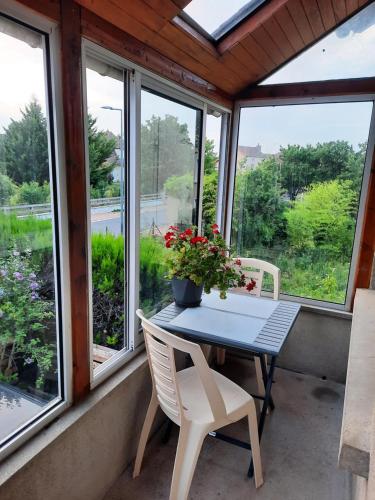 einen Tisch und Stühle auf einer Veranda mit Fenstern in der Unterkunft Logement entier à Gannat in Gannat