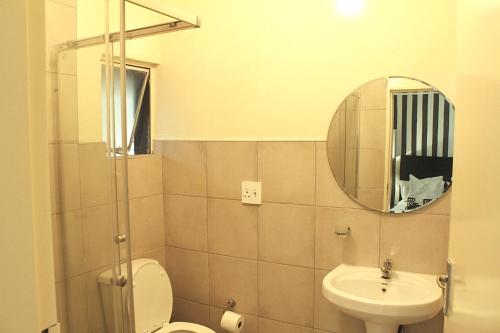 a bathroom with a toilet and a sink and a mirror at Exquisite 1-Bed Apartment in Sandton in Johannesburg