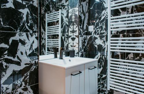 une salle de bains avec un lavabo blanc et des carreaux noirs dans l'établissement Paillette, au Havre